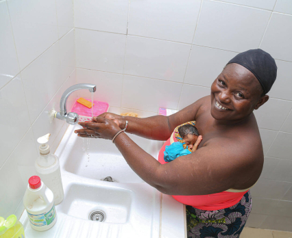 Matka z nowo narodzonym dzieckiem myje ręce