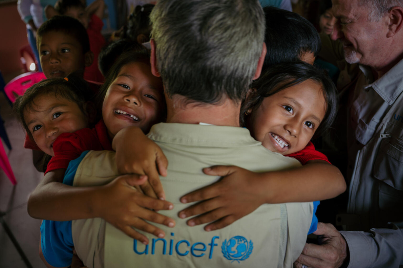 Dzieci przytulają się do pracownika UNICEF.