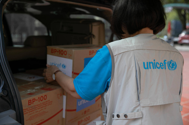 Pracownica UNICEF układa kartony z żywnością terapeutyczną.