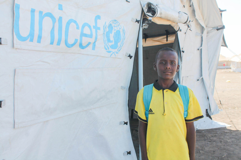 Trzynastoletni Taha przed namiotem UNICEF