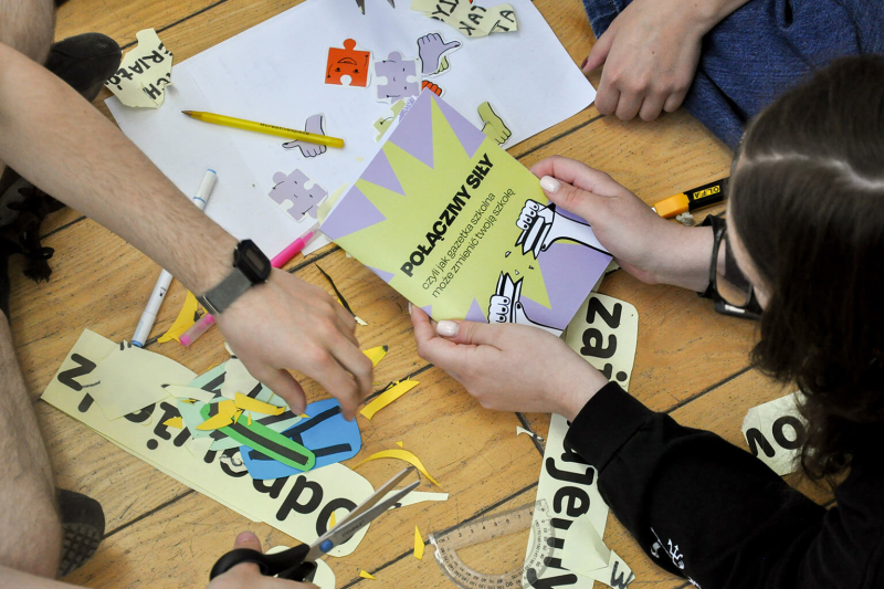Grupa dzieci przygotowuje gazetkę szkolną, korzystając z materiałów instruktażowych, które powstały w ramach współpracy UNICEF Polska i ASP.