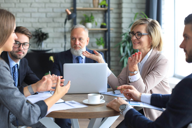 Udziałowcy spółki siedzą przy stole i omawiają bieżące kwestie w trakcie spotkania zarządu.