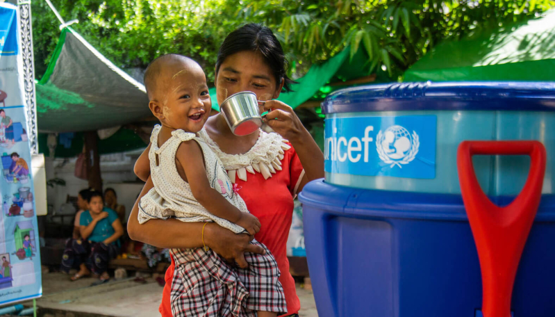 Ma Aye Su poi swoje dziecko wodą ze zbiornika UNICEF