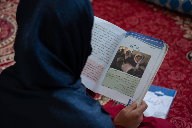 Wahida czyta podręcznik w domu, pr&oacute;bując samodzielnie się uczyć.