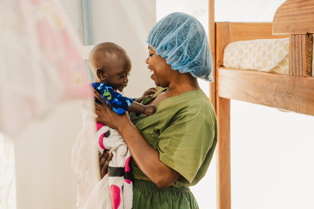 Pracownica UNICEF z małym dzieckiem na rękach